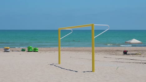 An-empty-yellow-football-goal,-also-known-as-football-gate,-is-seen-at-the-beach-on-the-shore-of-the-Mediterranean-sea-in-Alicante,-Spain