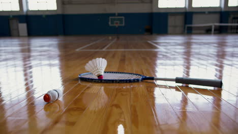 badminton racket and shuttlecock on a court floor