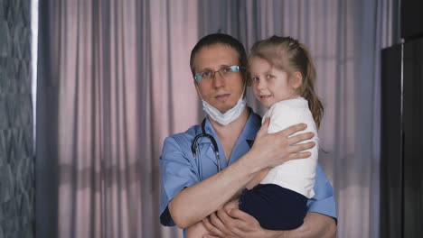 el médico en uniforme se quita la máscara protectora y sostiene a la chica.