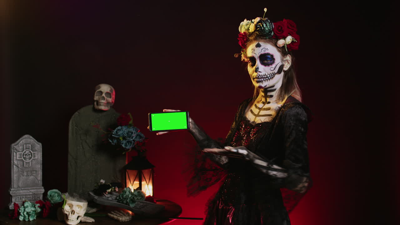 Woman in Day of the Dead makeup holding a green screen phone