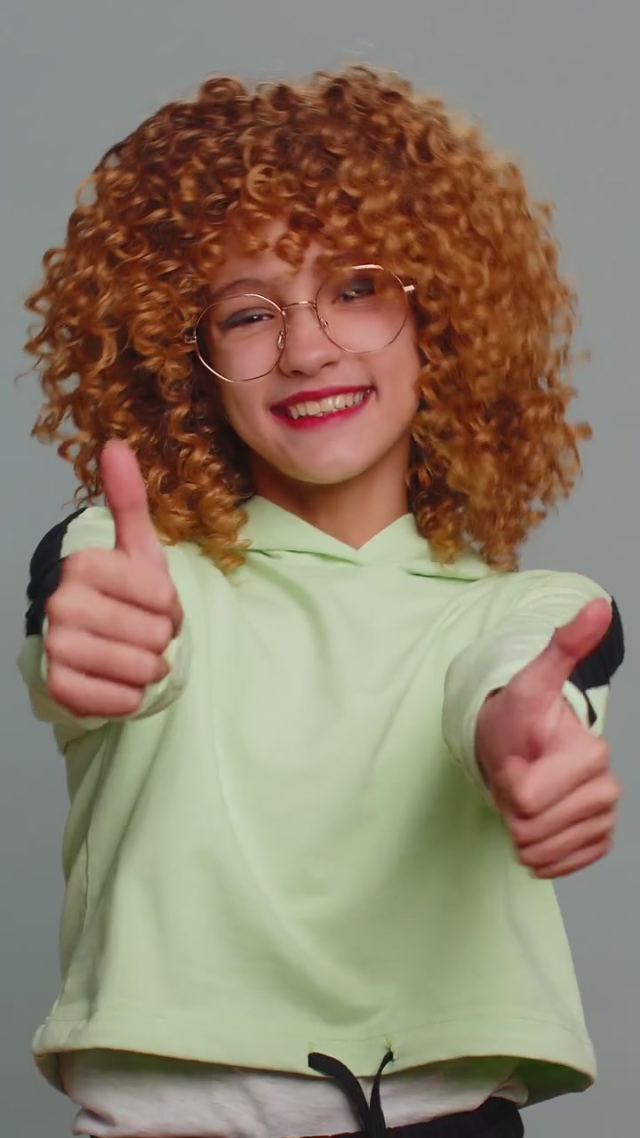 Happy teenager child girl kid looking approvingly at camera showing thumbs up like positive sign