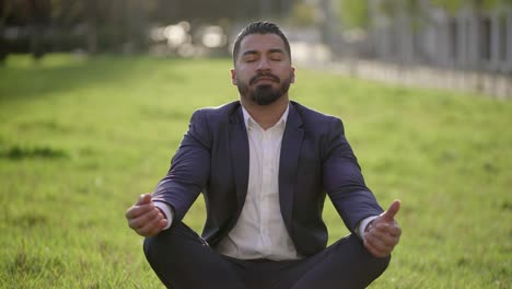 Hombre-De-Negocios-En-Traje-Meditando-Sobre-La-Hierba-Verde