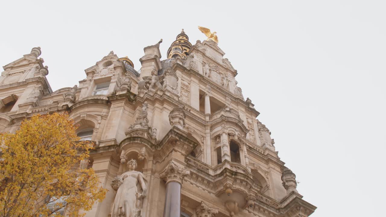 안트베르펜의 조각상과 황금 새와 함께 중세 전면 건물이 약간 위쪽으로 기울어져 있습니다.