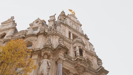 medieval facade building with statues and golden bird looking up with a slight tilt upwards in antwerp