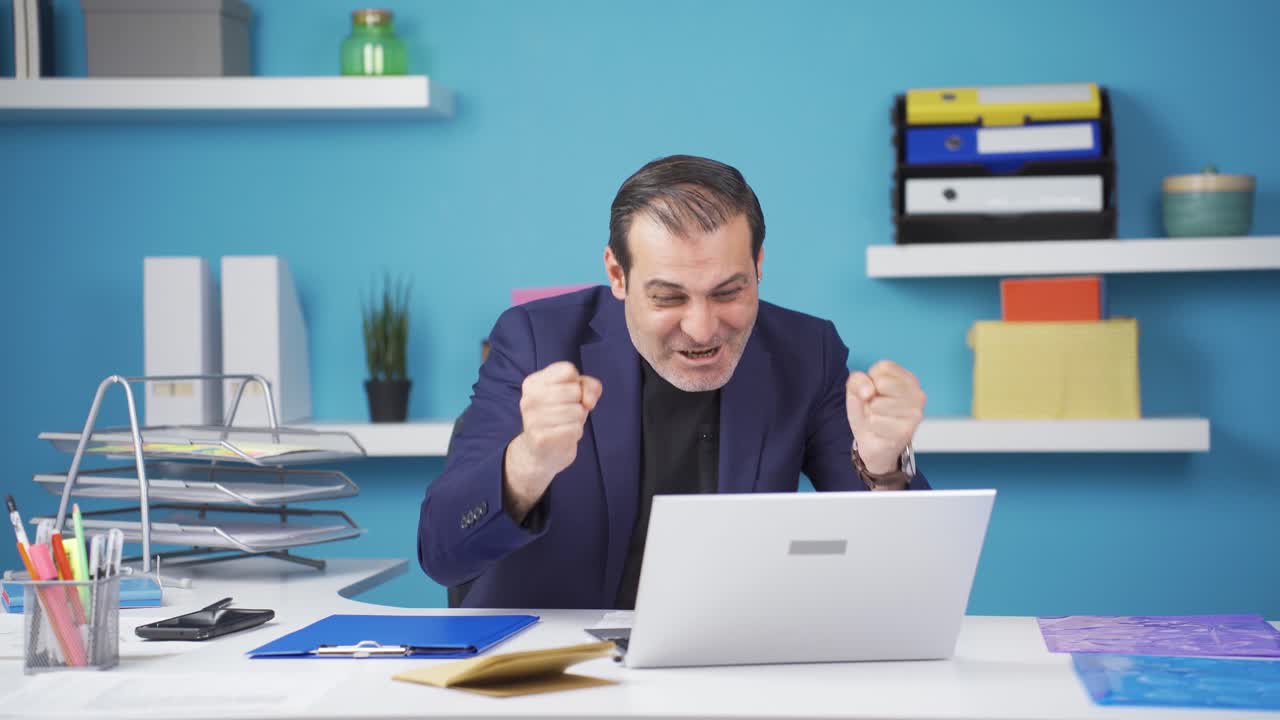 Happy businessman getting good results on laptop.