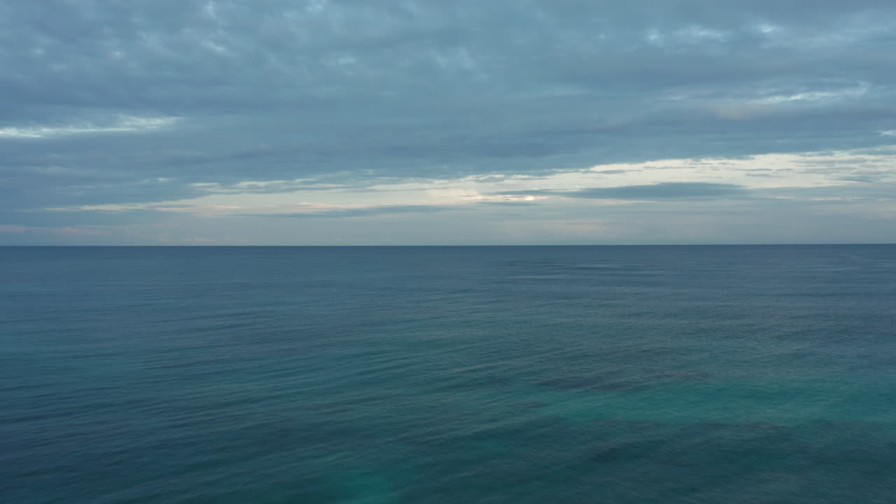 캐리비안 바다는 흐린 하늘이 일몰을 향해 수평선으로 사라집니다.