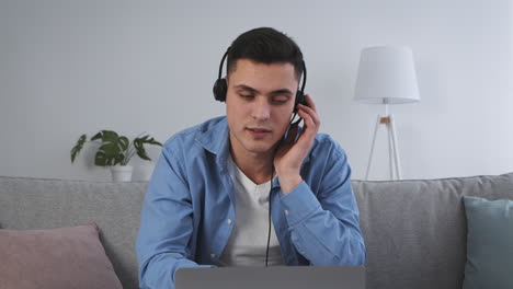 hombre en auricular usando computadora portátil en el sofá