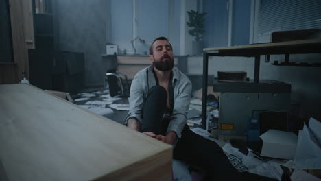 man sitting on the floor of a chaotic office