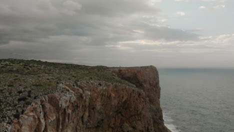 4k aerial view of a rock cliff with the sea background in denia, alicante, spain, wide angle approach shot