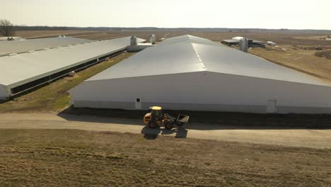 farmer hauling feed at a hog confinement with a skid loader outdoors