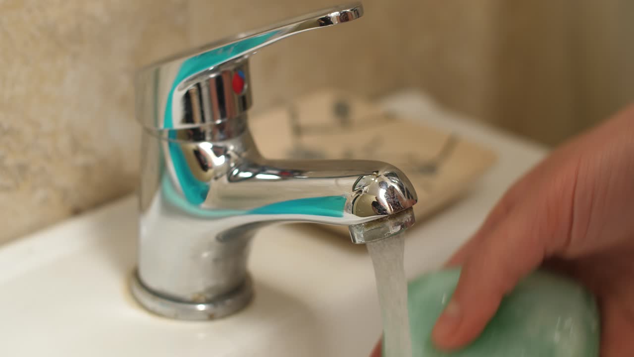 Persona che si lava le mani con il sapone sotto l'acqua corrente dal rubinetto.