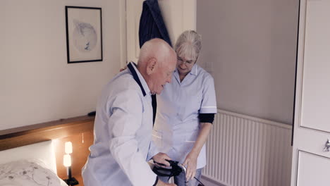 elderly man receiving assistance from caregiver with a walker in a bedroom