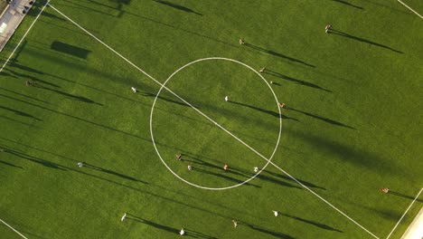 Vista-Aérea-De-Arriba-Hacia-Abajo-De-Un-Campo-De-Fútbol-Verde-Con-Gente-Jugando