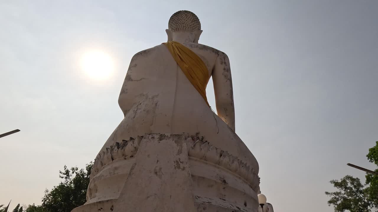 el sol se pone detrás de una gran estatua de buda