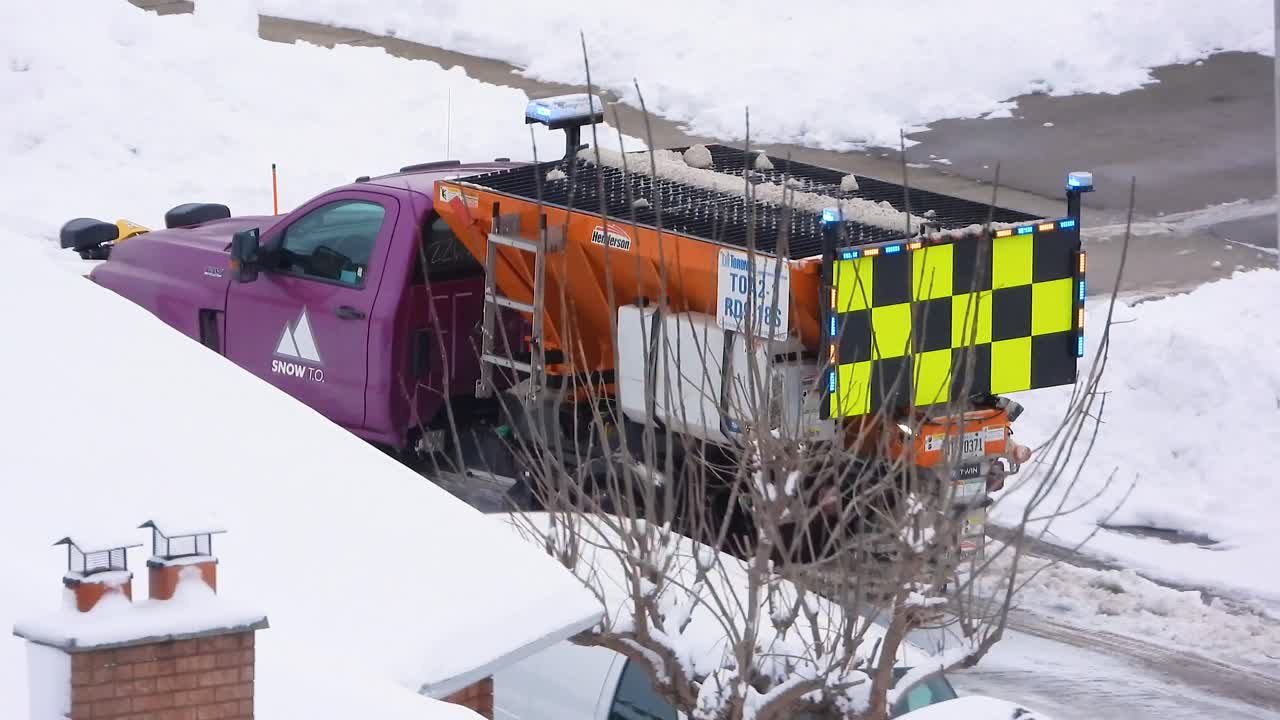Purple Snow Plow Truck Clearing Snow from Residential Street in Canada