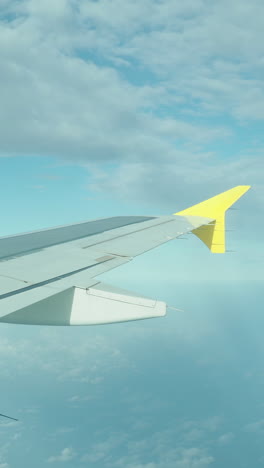 view from a plane window of the sky with the wing of the plane in shot in vertical