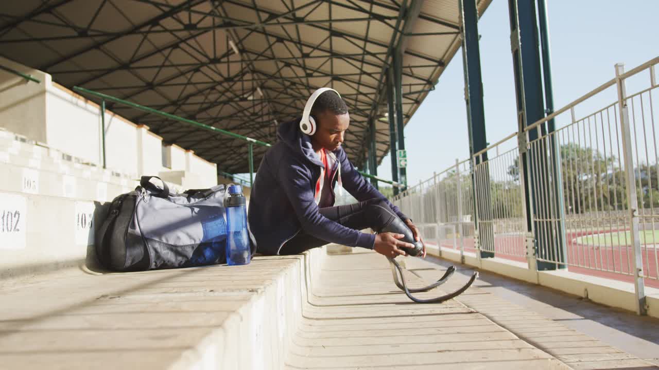 Disabled mixed race man with prosthetic legs listening to music on headphones