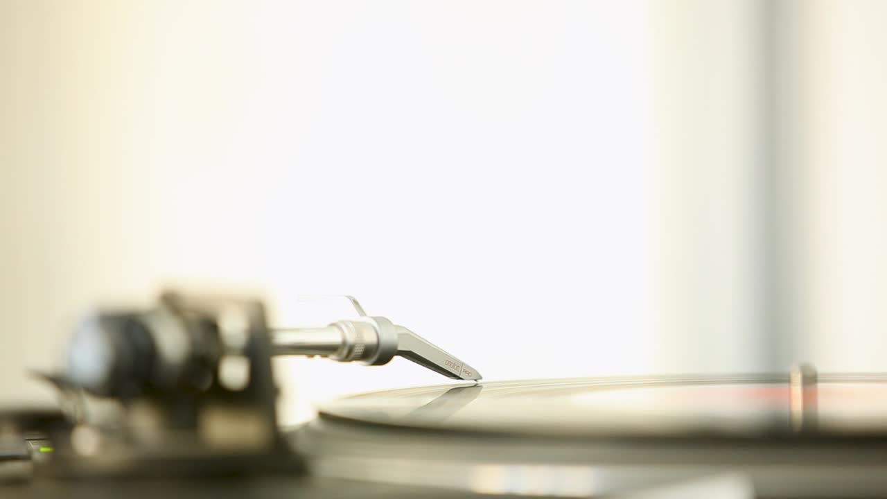 밝은 방에서 비닐 레코드에 바늘을 넣는 손의 클로즈업