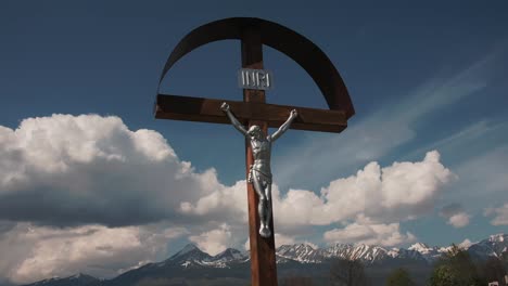 cross with jesus in front of mountains with clouds