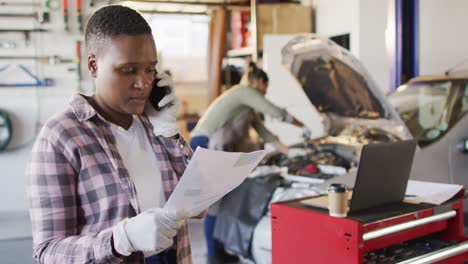 Video-of-african-american-female-car-mechanic-reading-documents