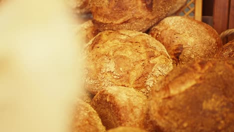 a hand picks out a fresh loaf of bread from a basket