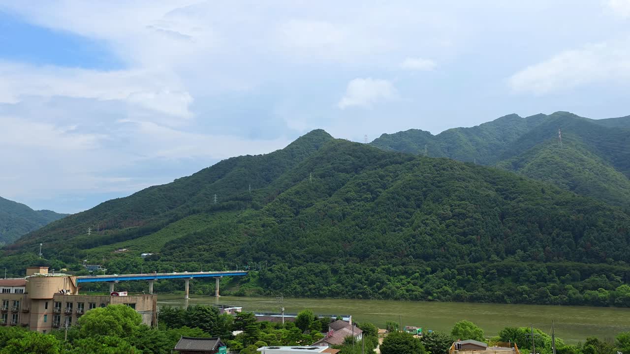 Sweeping aerial pan reveals the New Cheongpyeong Bridge crossing the Bukhan River after showcasing the lush green Cheongpyeong Valley mountains in Gapyeong