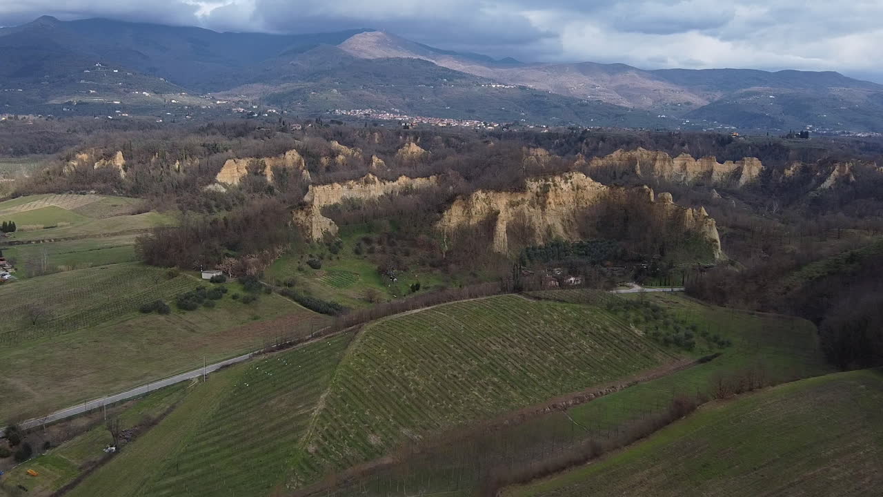 Far approaching Aerial flying drone shot over prehistoric age canyons Le Balze natural reserve near Reggello. Tuscany, Chianti area. Italy. Winter season, partially sunny sunset