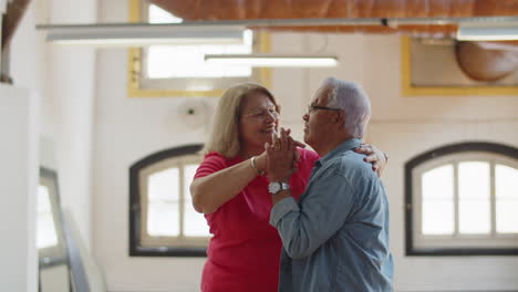 medium shot of happy senior couple dancing together in ballroom