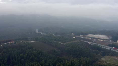 Vehicles-Driving-On-Asphalt-Road-In-Porto,-Portugal-On-A-Foggy-Morning---aerial-drone-pullback