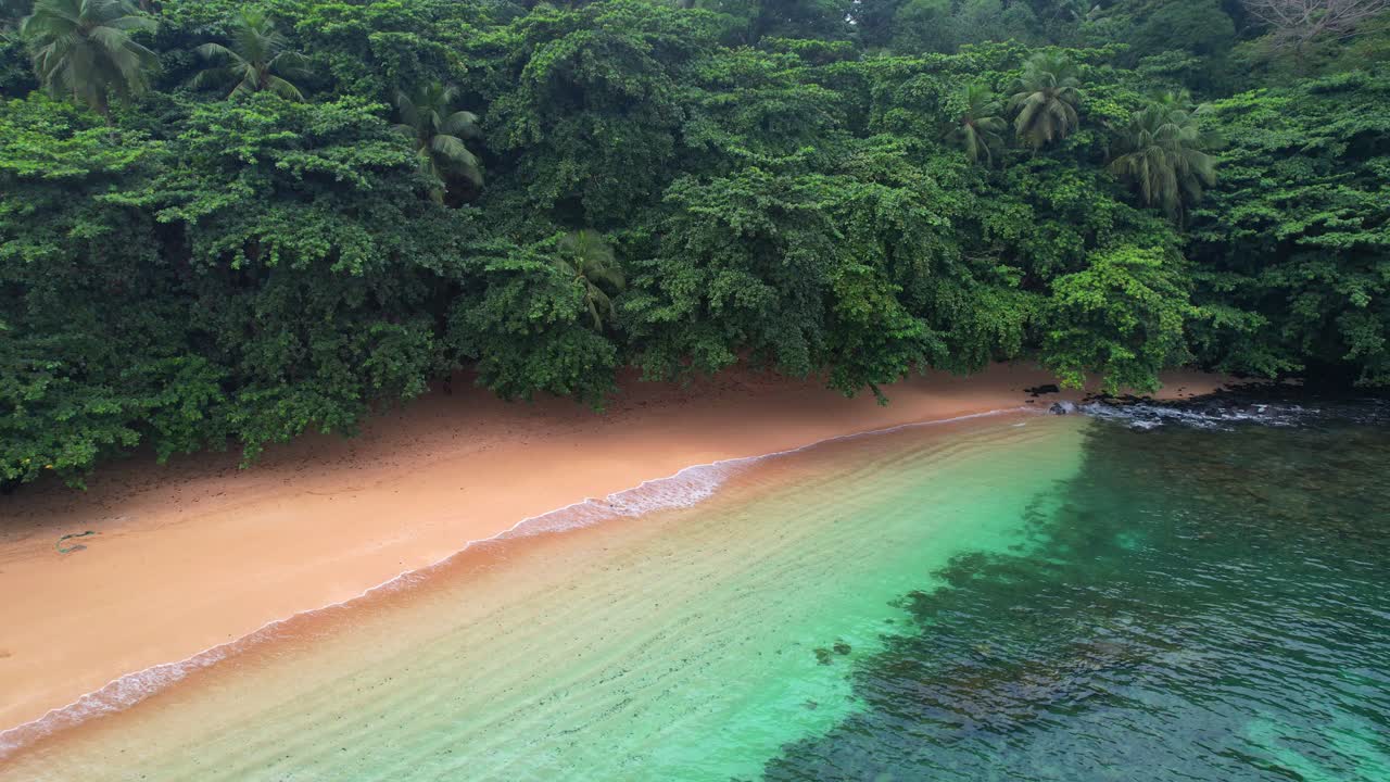 Aerial backwards view from the transparant sea of Margarida beach with a boat anchored at se beach. Ilha do Principe (Prince Island),Africa