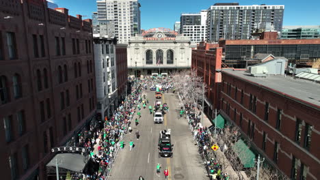 Drone-shot-of-parading-trucks-driving-slowly-down-the-downtown-streets-of-Denver,-Colorado-for-St