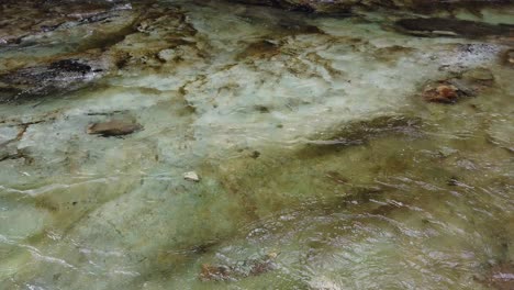 water flows smoothly across layered rocks with mossy green texture, peaceful zen scene