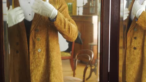 man in vintage formal attire looking in a mirror in an antique house