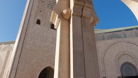 Casablanca's-Hassan-II-Mosque,-tracking-shot-of-Minaret-from-courtyard-arches,-Morocco