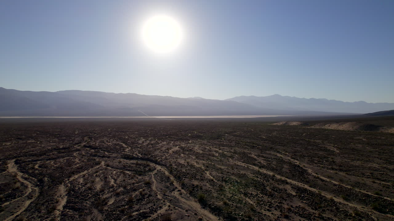 muñeca aérea a través del paisaje seco del lecho del río del desierto con un sol redondo brillante en el cielo