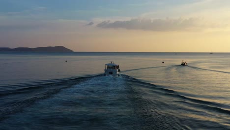 cinematic aerial dynamic zoom out shot, following a private cruise ship sailing out into the ocean at sunset golden hour at langkawi island, malaysia, southeast asia