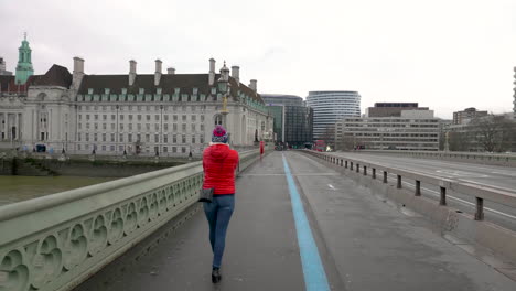 british women walking along an empty westminster bridge while a police motorcycle and a double decker bus pass by