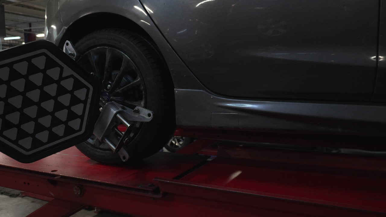 Ruota di automobile con attrezzatura per il sensore di allineamento in un'officina meccanica.