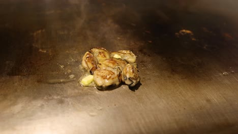 oysters sizzling on a hot, metallic surface