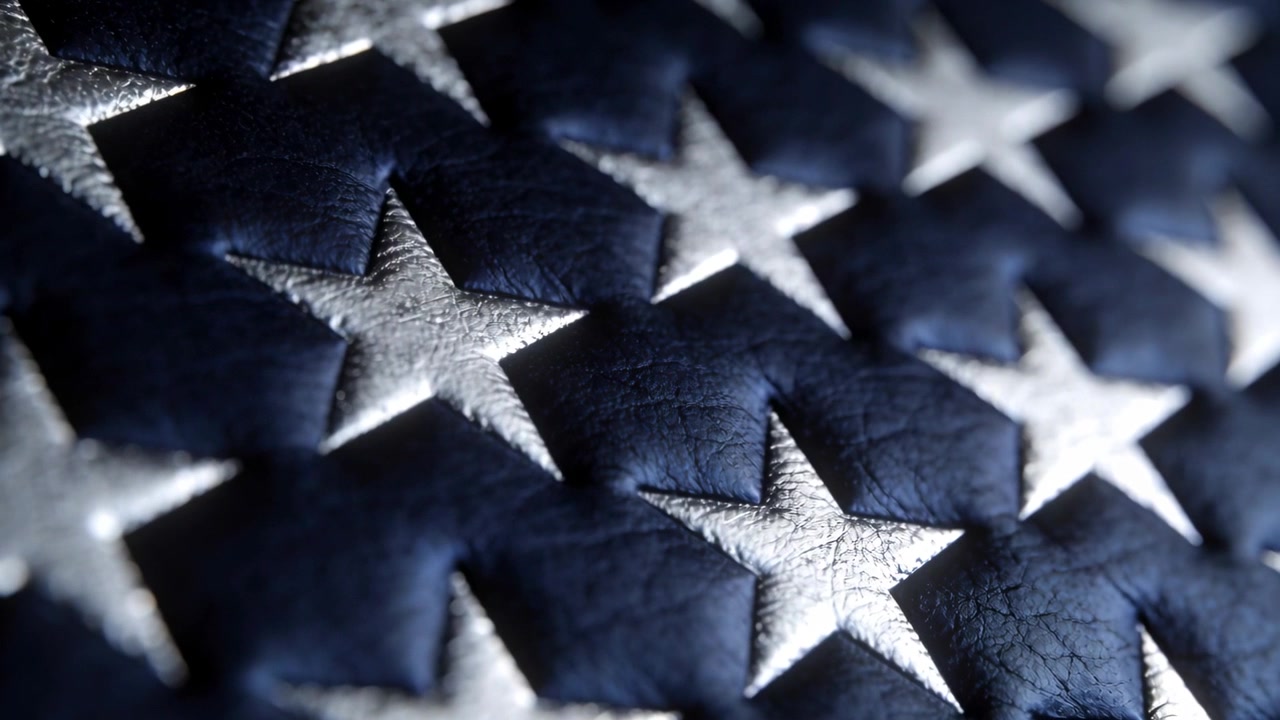 Shifting camera revealing silver stars on deep blue leather fabric, showing stitching and cracks
