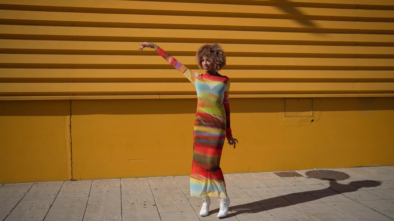 Una modella alla moda ed elegante posa con grazia contro un muro giallo vibrante e luminoso.
