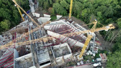 vista aérea construcción de un nuevo edificio con grúas de torre altas en área verde