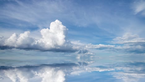 futuristic background consisting of time lapse clip of white fluffy clouds over blue sky and their reflection, video loop