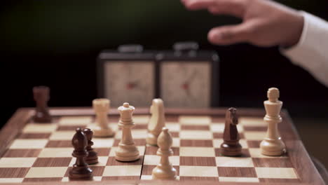 hands of two chess players alternate, removing some pieces from the board while stopping the clock