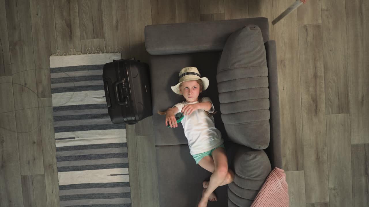 mamá viene a la niña acostada en el sofá y jugando con gafas de sol