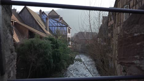 scenic wide shot of half-timbered houses near the weiss river stream flowing through medieval town in france, kaysersberg