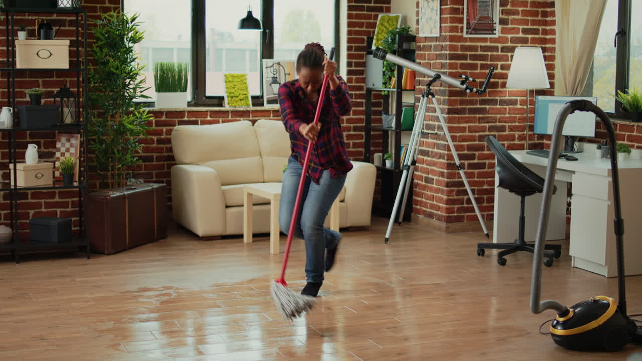 Modern housewife doing dance moves in living room and mopping wooden floors