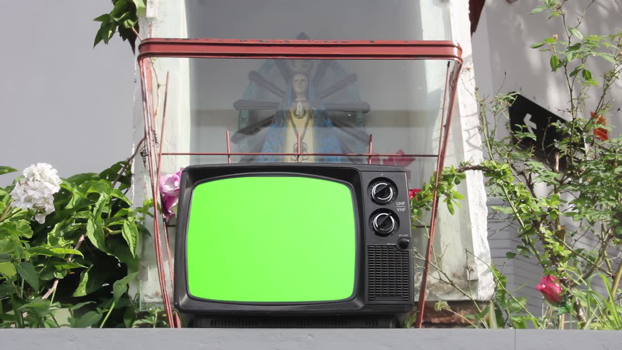 오래된 tv 세트가 거리의 제단에서 녹색 화면을 켜고 있습니다.