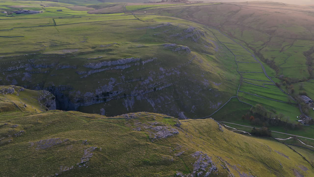 Soaring aerial footage showcases the dramatic limestone ravine of Gordale Scar, near Malham in North Yorkshire, England. Witness the unique geological formations of this stunning natural wonder