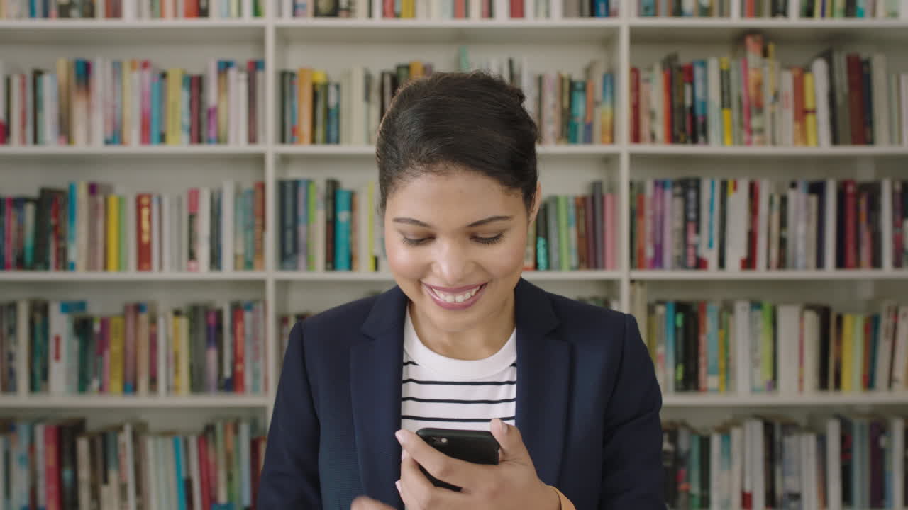 retrato de una joven estudiante usando un teléfono inteligente estantería de la biblioteca de la universidad